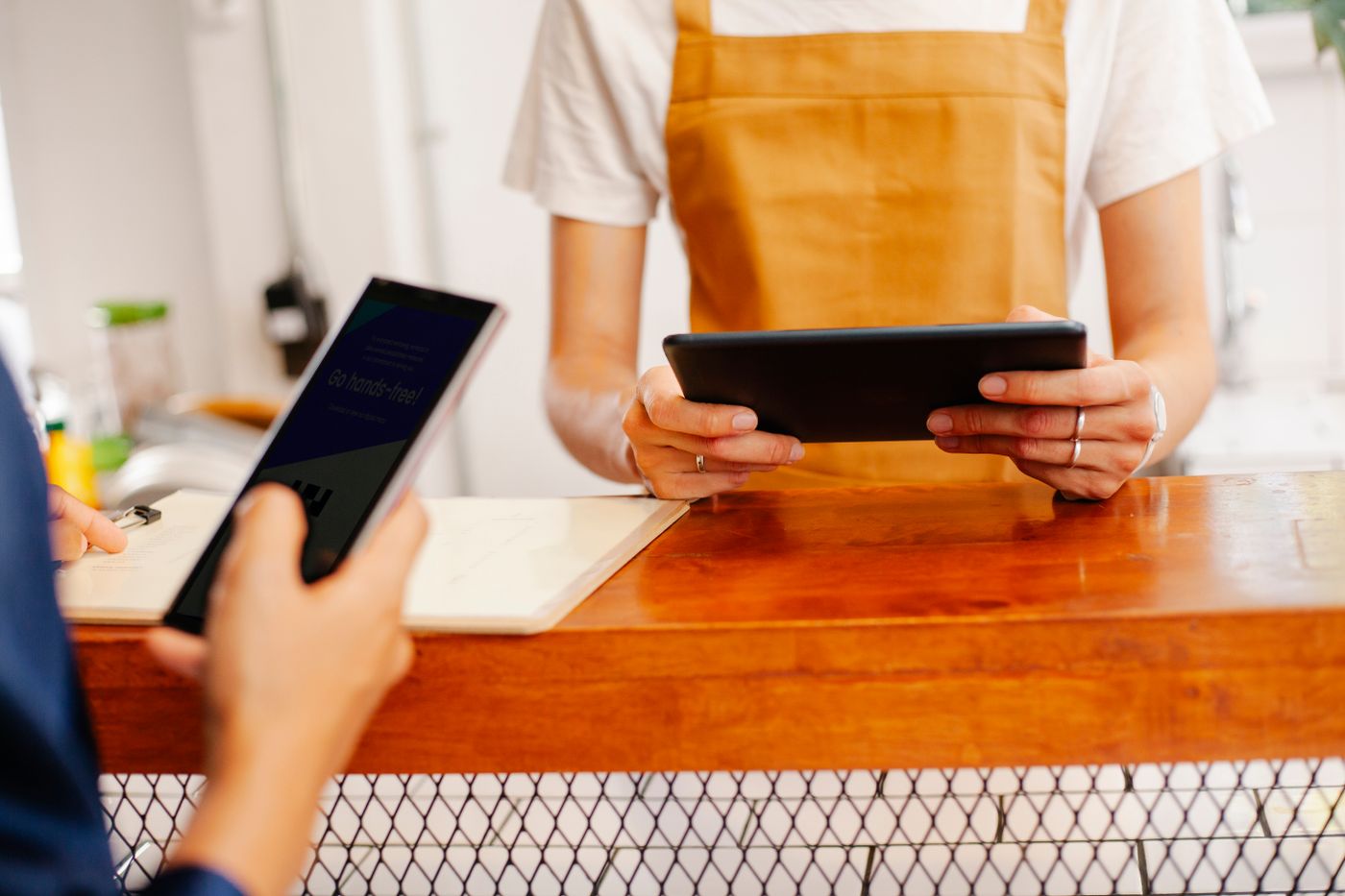 Café staff managing tablets and paperwork at the counter